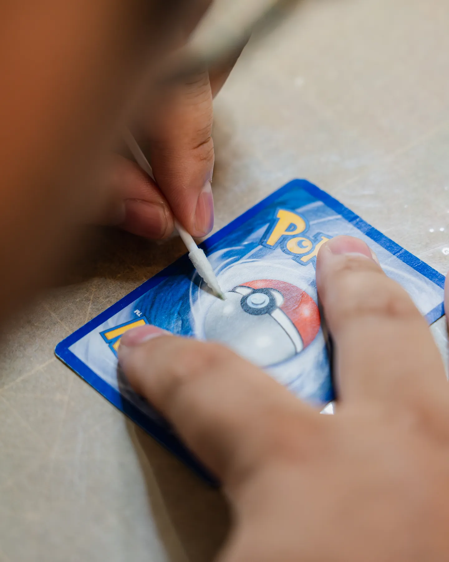 A Pokémon card being restored by hand at Cappy's Cards