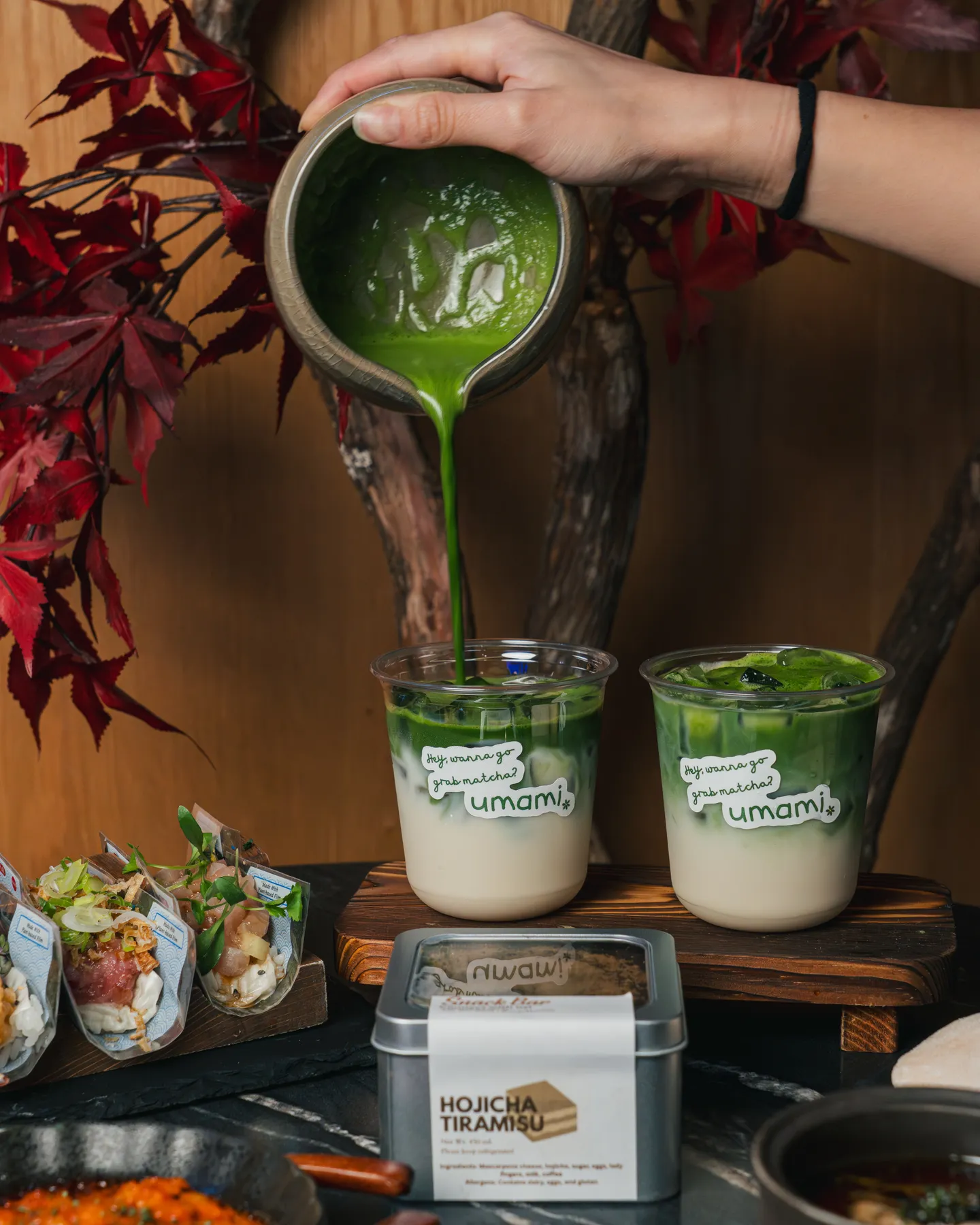 Matcha being poured beside snacks and red leaves at Umami Matcha